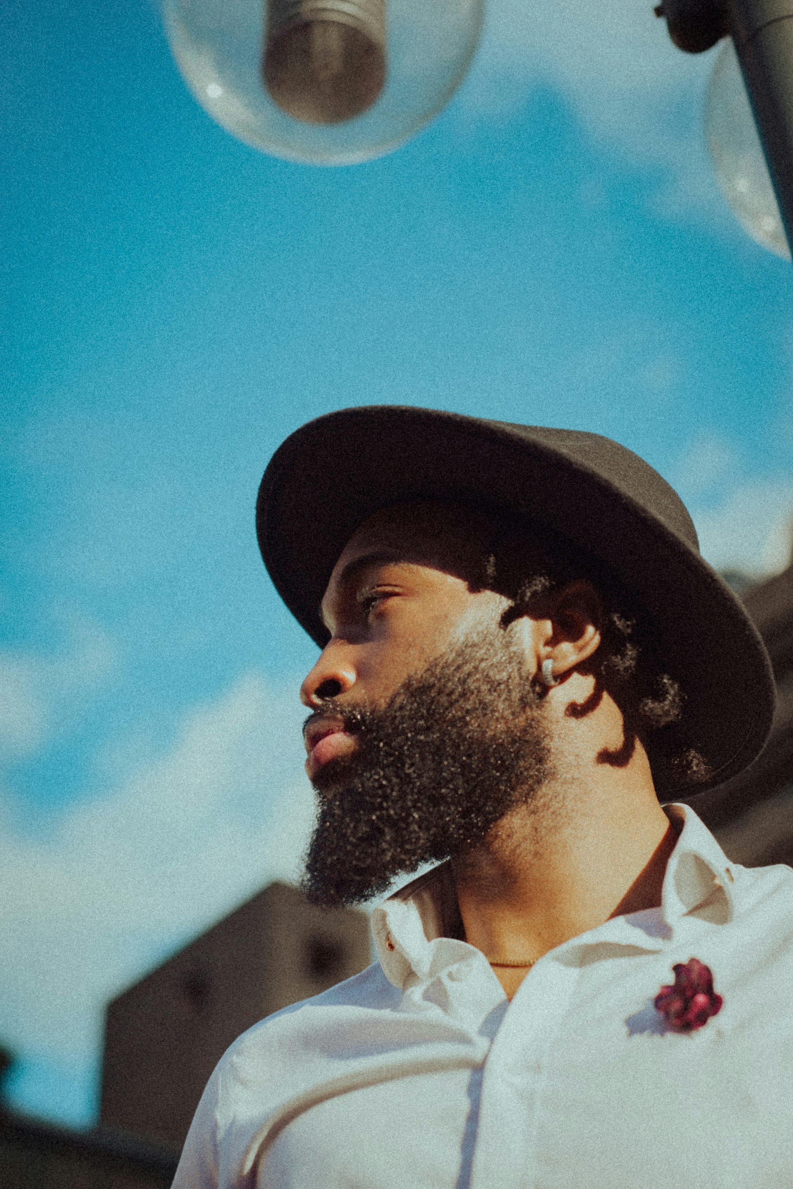 Dramatic low-angle portrait in a hat against a blue sky
