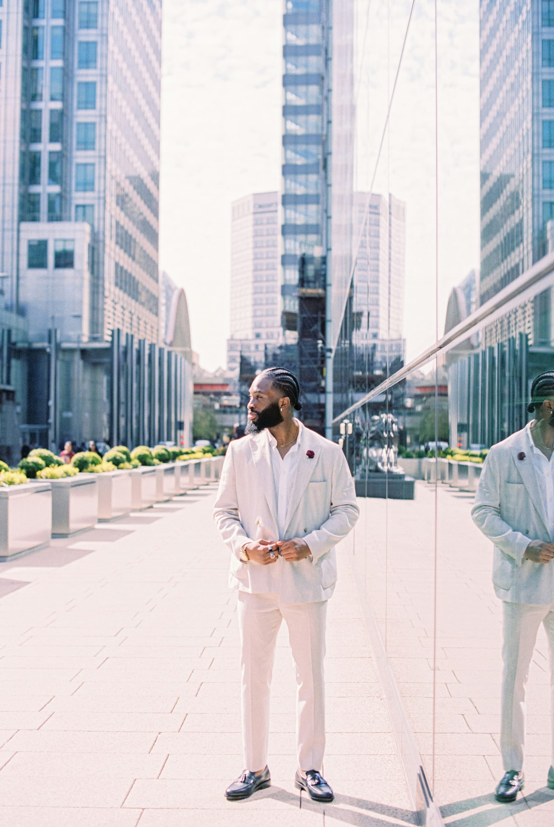 Full-body portrait in a white suit with city glass reflection